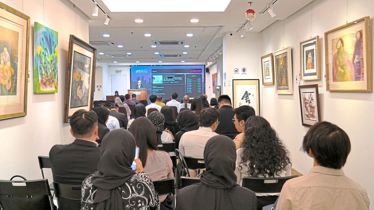 Bidders in the NCM Co auction hall discussing a property offering in Kuala Lumpur. 