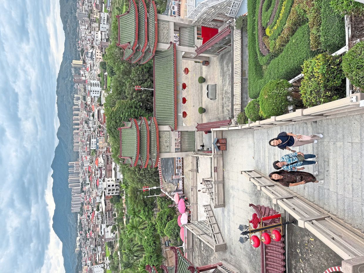 The writer’s mother (centre), his wife (right) and Xiaoyan (left) are pictured with the scenic backdrop of Shishan Town.