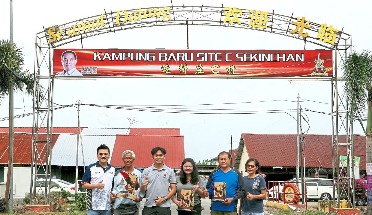 Gan (third from left), Fu (far left), Chia (third from right) and locals holding the awards. Kampung Baru Sekinchan Site C in Sabak Bernam won second place in the state competition. It also won two other awards.