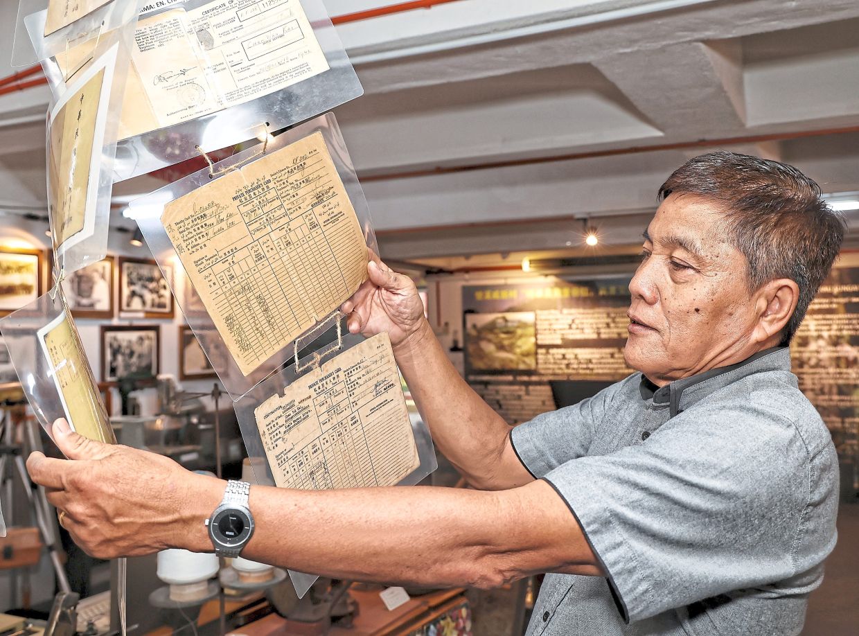 Ding showing old private purchasers’ cards on display at the corridor.