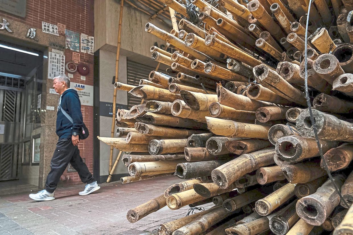 A pedestrian walking past bamboo used for scaffolding in Mong Kok district. — AP