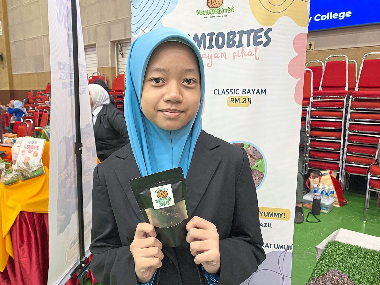 Nurawatiff Yusrina holding a packet of spinach cookies.