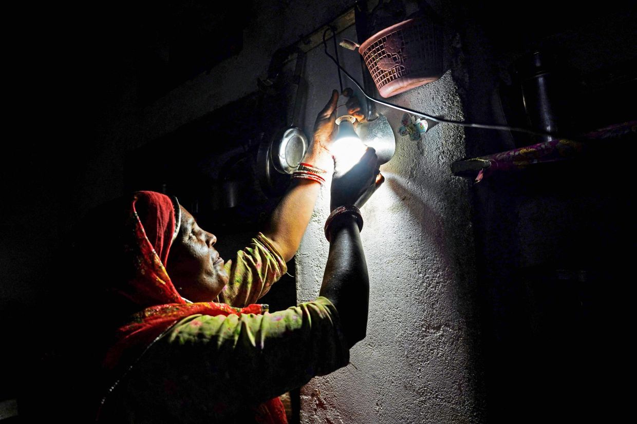 Lighting the way: Santosh putting in a light bulb at her house in Rajasthan. — AFP