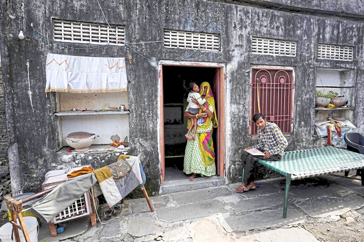 Trying to make ends meet: Champa holding her son as Vinod sits on a charpoy at their house in Rajasthan. Champa has fixed a few solar panels. — AFP