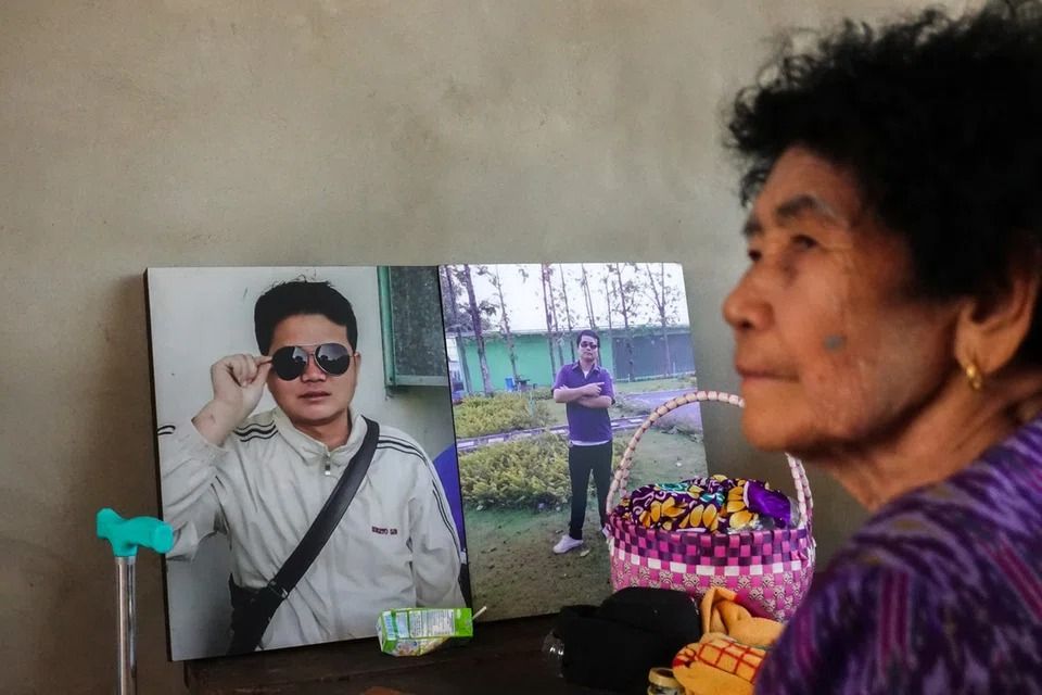 Sudthisak Rinthalak's mother, On Rinthalak, 80, sits next to pictures of her son at their house in Thailand, on Dec 5. -- PHOTO: REUTERS
