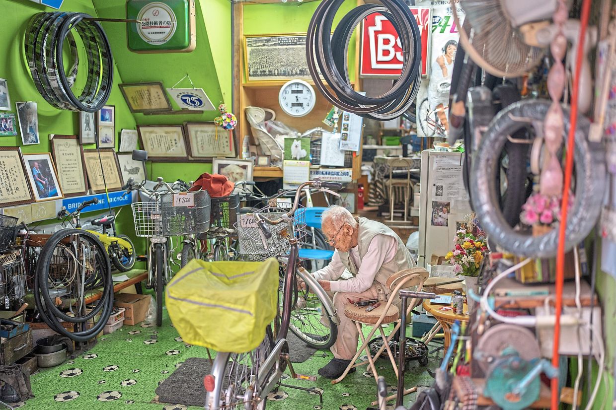 Ishii, 103, a bike repairman, working on a bike at his shop in Tokyo. He learnt how to repair a bike when he was 12 years old.