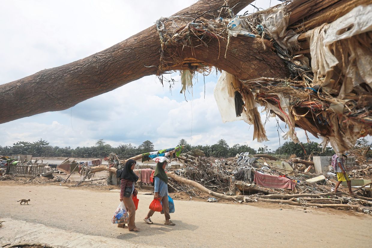 Staying resilient: Survivors walking past debris at an area devastated by flash flood in Aceh Tamiang on Sumatra island. — AP