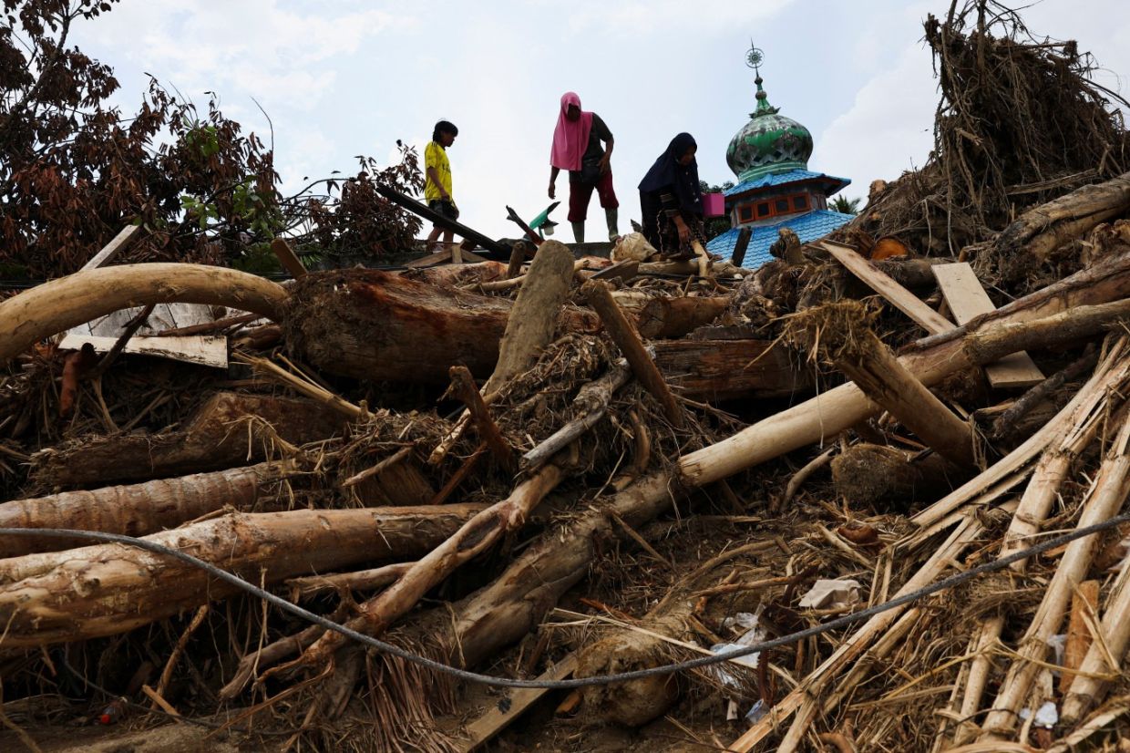 Residents climb over logs in walk to aid centre as flood deaths in Aceh rise over 900