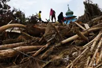 Residents climb over logs in walk to aid centre as flood deaths in Aceh rise over 900