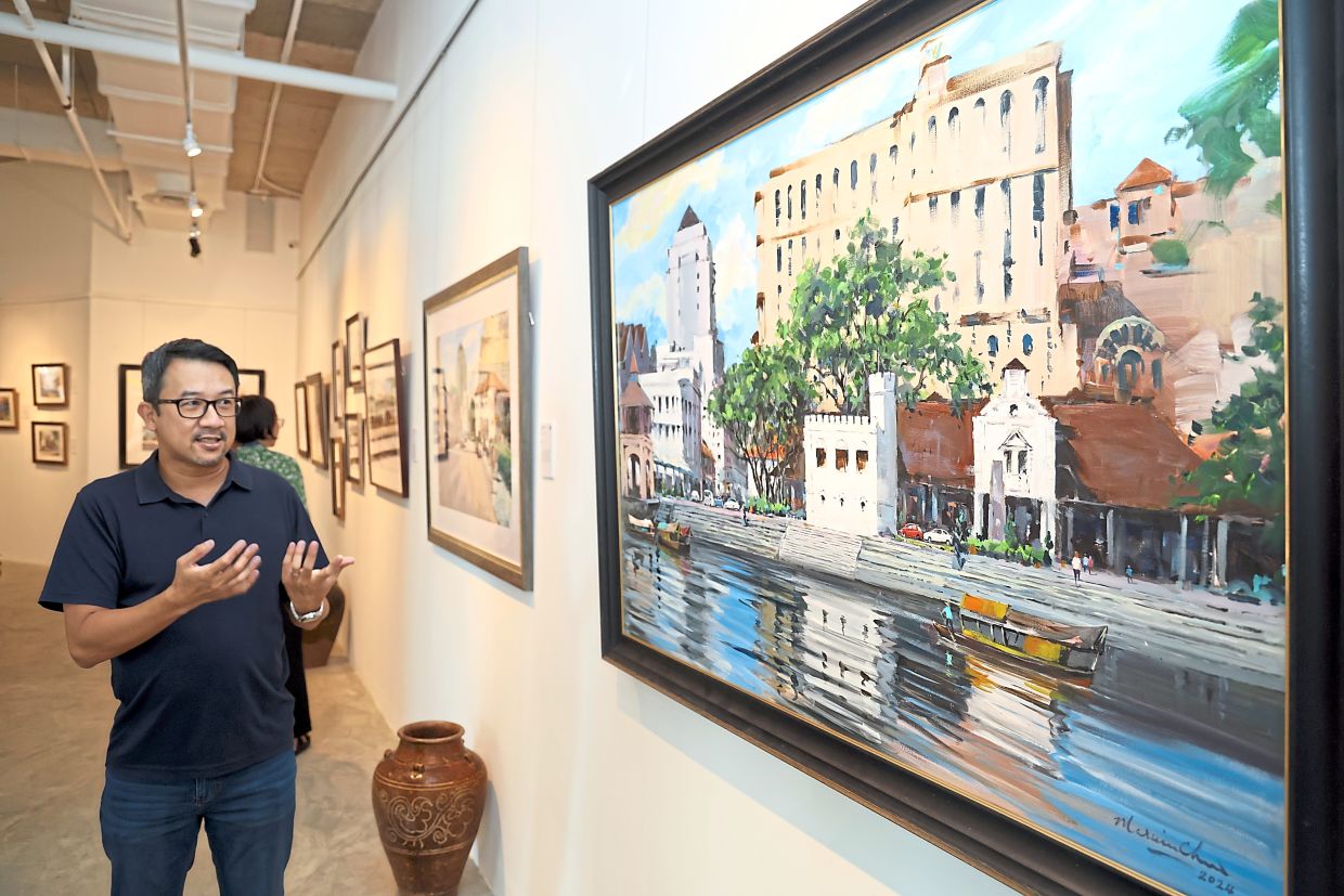 Chew showing a painting of the Kuching Waterfront and other artworks (below) at his solo exhibition. 