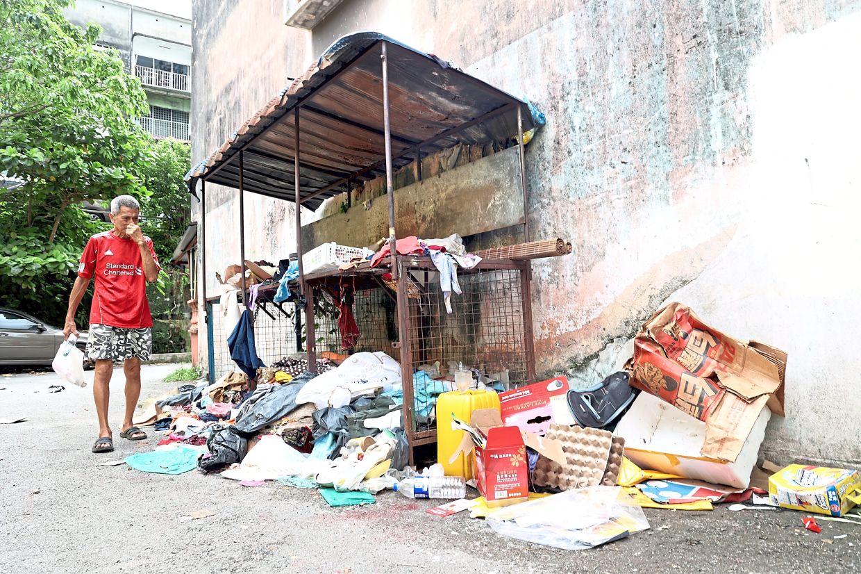 A resident walking past an ageing recycling cage with waste all over the place at Jalan Sepadu 5 in Taman United, KL.