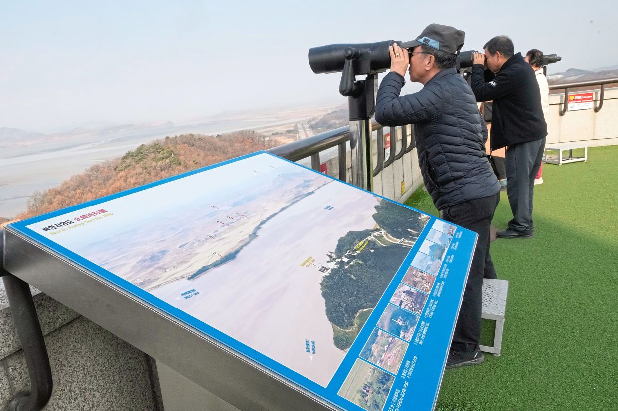So close, yet so far: Visitors observing the North Korean side from the Unification Observation Post in Paju, South Korea. Paek at his office in Seoul. — AP