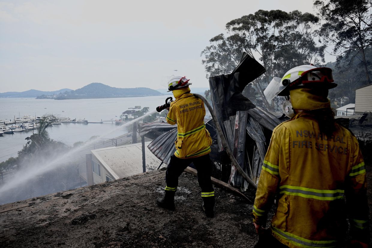 Australian bushfires raze homes in two states; firefighter dies