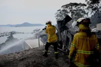Australian bushfires raze homes in two states; firefighter dies