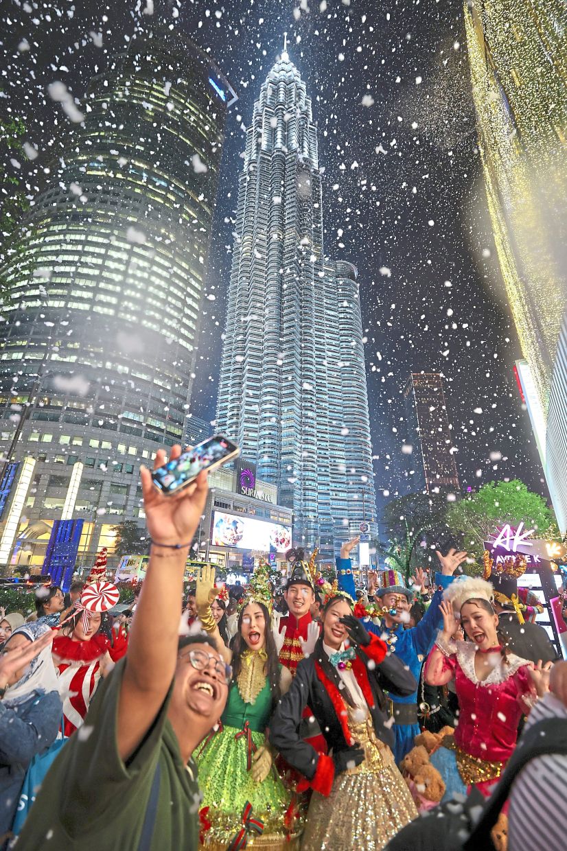 Visitors immersing themselves in a snowfall at avenue K in Kuala Lumpur. — ZULAZHAR SHEbLEE, GLENN GUAN and YAP CHEE HONG/The star