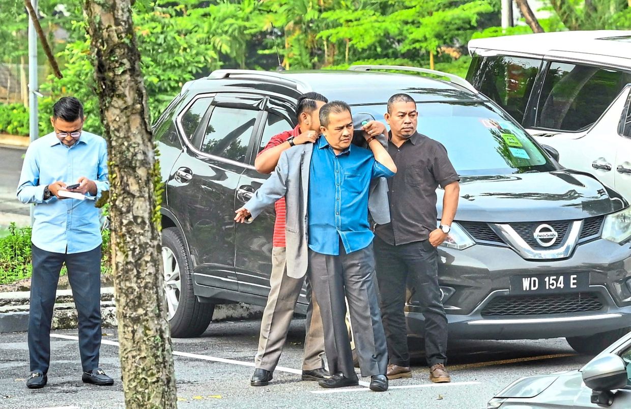 Day in court: Azman (centre) arrives at the Shah Alam Sessions Court ahead of claiming trial to a charge of abetting corruption involving a Kedah cattle feedlot project. — RAJA FAISAL HISHAN/The Star