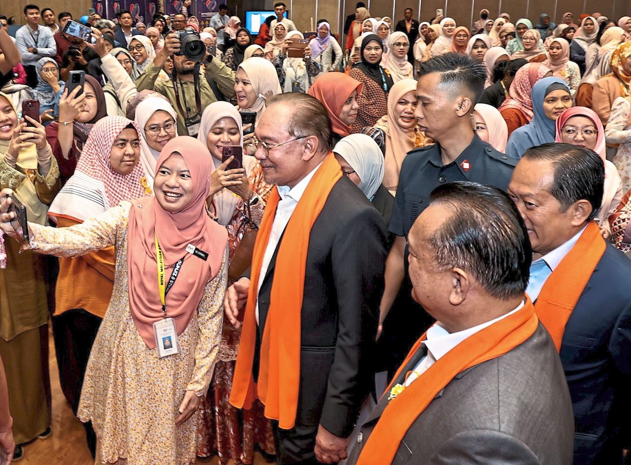 All smiles: Anwar posing for a photo with the Works Ministry staff after attending the monthly assembly at Dewan Tan Sri Mahfoz Khalid. — AZMAN GHANI / The Star