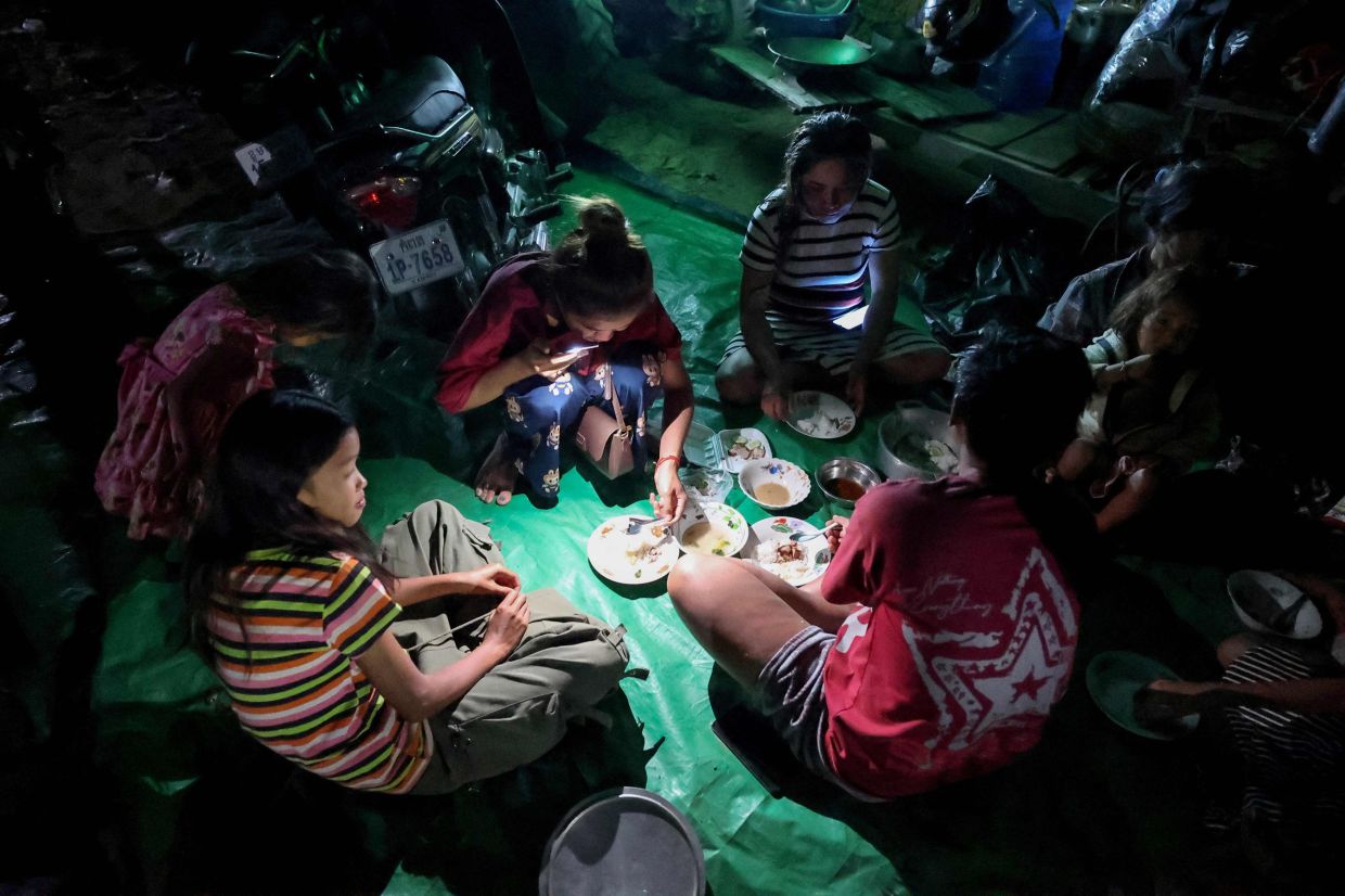 Residents having dinner after they evacuated following clashes along the Cambodia-Thailand border in Srei Snam district in Siem Reap province on Dec 8, 2025. - AFP
