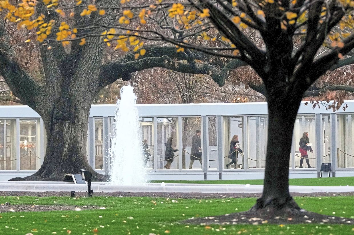 People walking through a newly constructed covered walkway on the North Lawn at the White House.