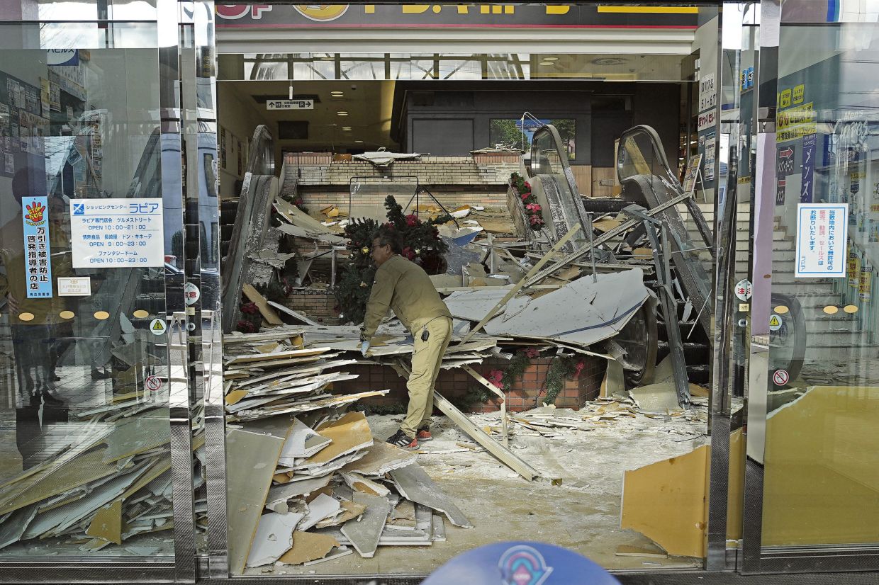 A man clearing debris from a commercial facility in Hachinohe, Aomori prefecture following the earthquake on Dec 8. - AP