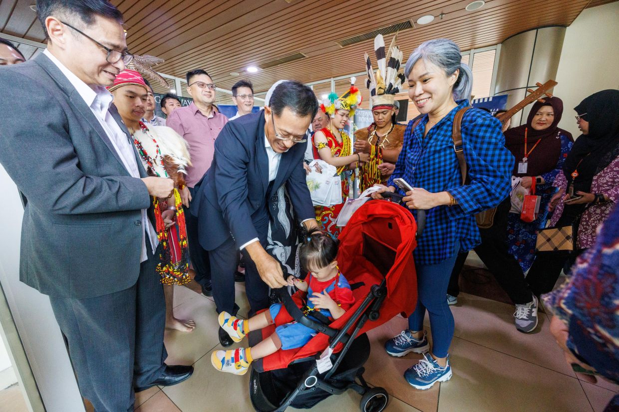 China's consul general in Kuching Xing Weiping (centre) welcoming a young passenger on the inaugural Loong Air chartered flight from Shenzhen at Kuching International Airport on Tuesday (Dec 9). - ZULAZHAR SHEBLEE/The Star