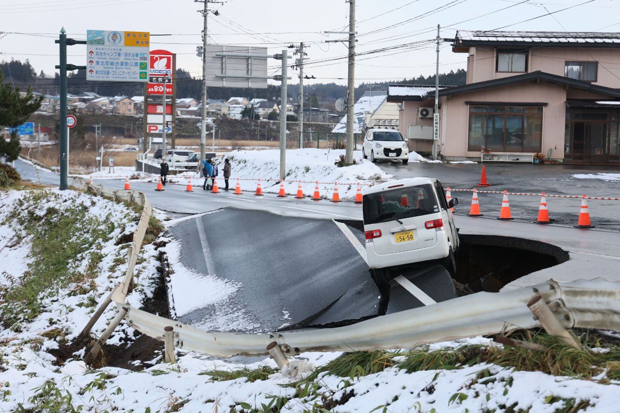 A vehicle rests on the edge of a collapsed road in Tohoku town in Aomori Prefecture on December 9, 2025, following a 7.5 magnitude earthquake off northern Japan. A big quake off northern Japan left at least 30 injured, authorities said on Tuesday, December 9, damaging roads and leaving thousands without power in freezing temperatures. -- Photo by JIJI Press / AFP
