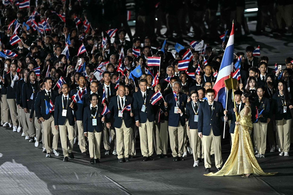 Members of Thailand's delegation wave their country's national flag as they take part in the athletes' parade during the opening ceremony of the 33rd Southeast Asian Games (SEA Games) at Rajamangala National Stadium. -- Photo by Lillian SUWANRUMPHA / AFP