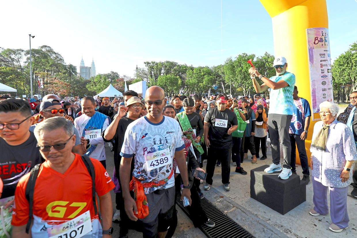 Khairy (standing on a box) officially starts the Batik Fun Walk 2025 with Leela (right).