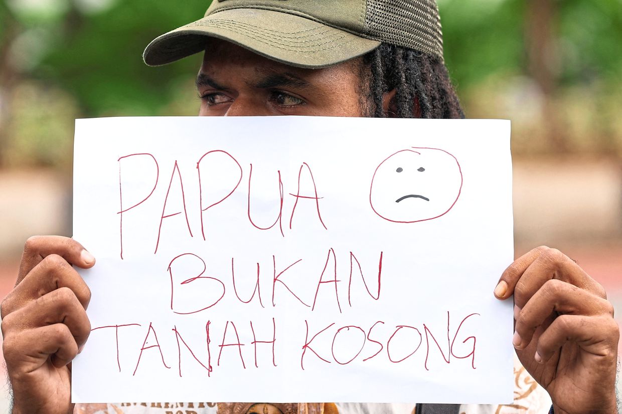 Lived experience: An activist holding a paper that reads ‘Papua is not an empty land’ during a protest outside the Agrarian and Spatial Planning/National Land Agency office in Jakarta. — Reuters