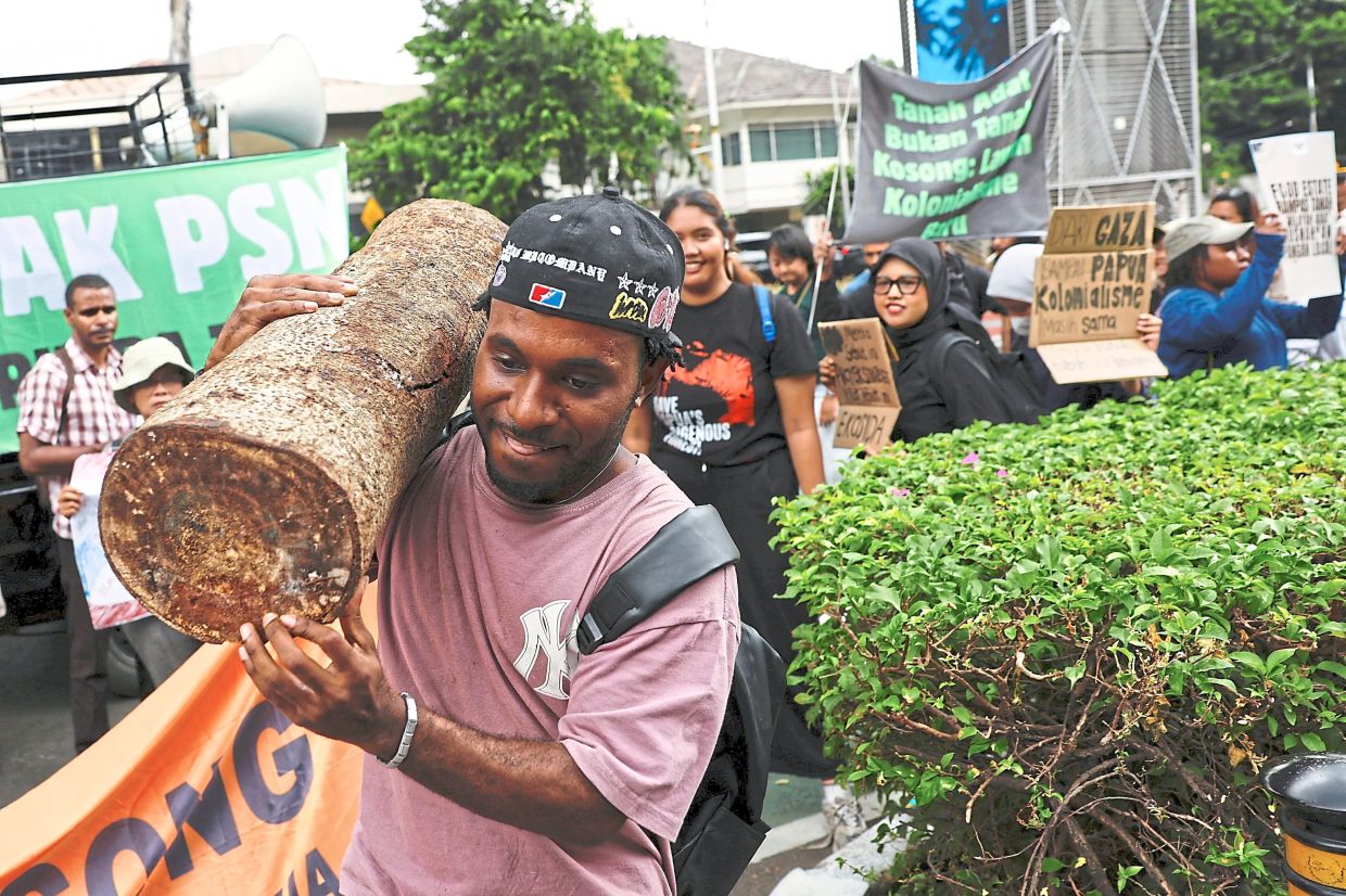 An activist carrying a piece of a tree trunk during a protest outside the office. — Reuters