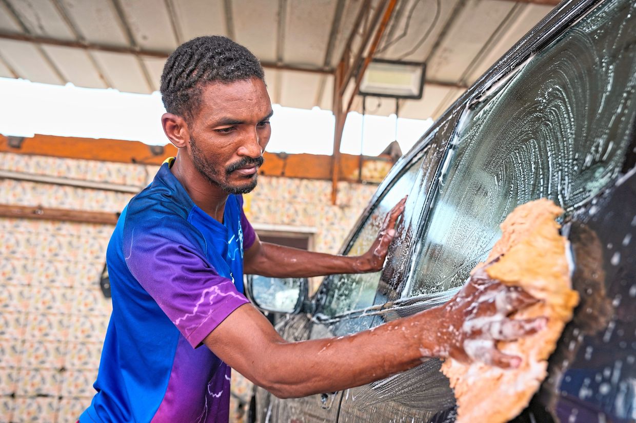 Dicko Hamidou, a herder who fled his village in Burkina Faso, works at a car wash in Abidjan.