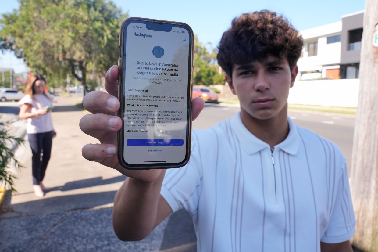Noah Jones shows a warning on his phone that says he cannot access a social media site as his mother Renee, walks toward him in Sydney on Dec 9, 2025. — AP