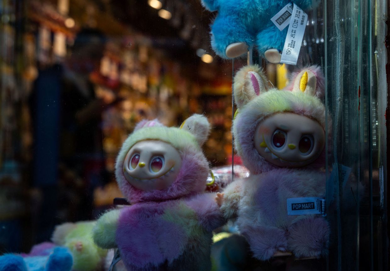 A man looks is silhouetted next to PopMart Labubu The Monsters dolls on display at a souvenir shop at the historical Shichahai district in Beijing, China, Nov 13, 2025. Photo: Reuters