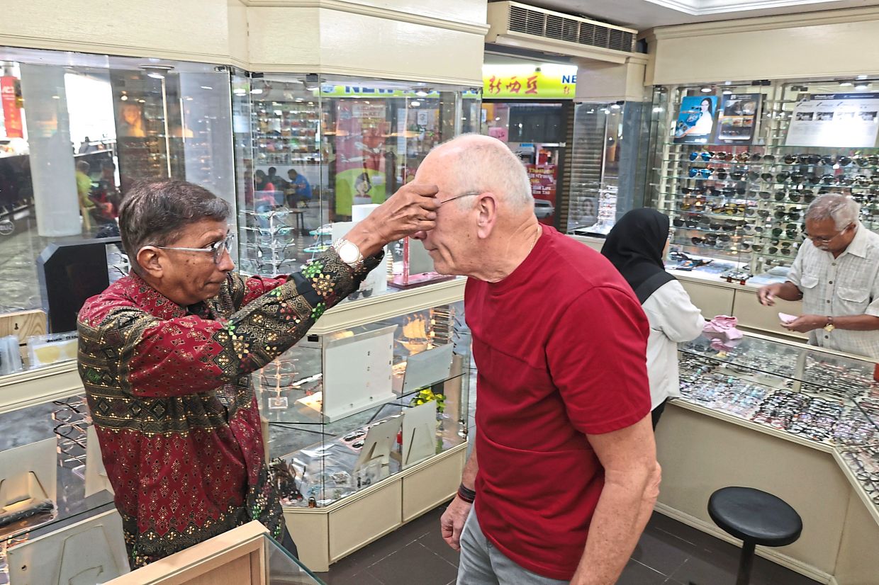 Komtar pioneer tenant Nickalas attending to a customer at his optical shop.