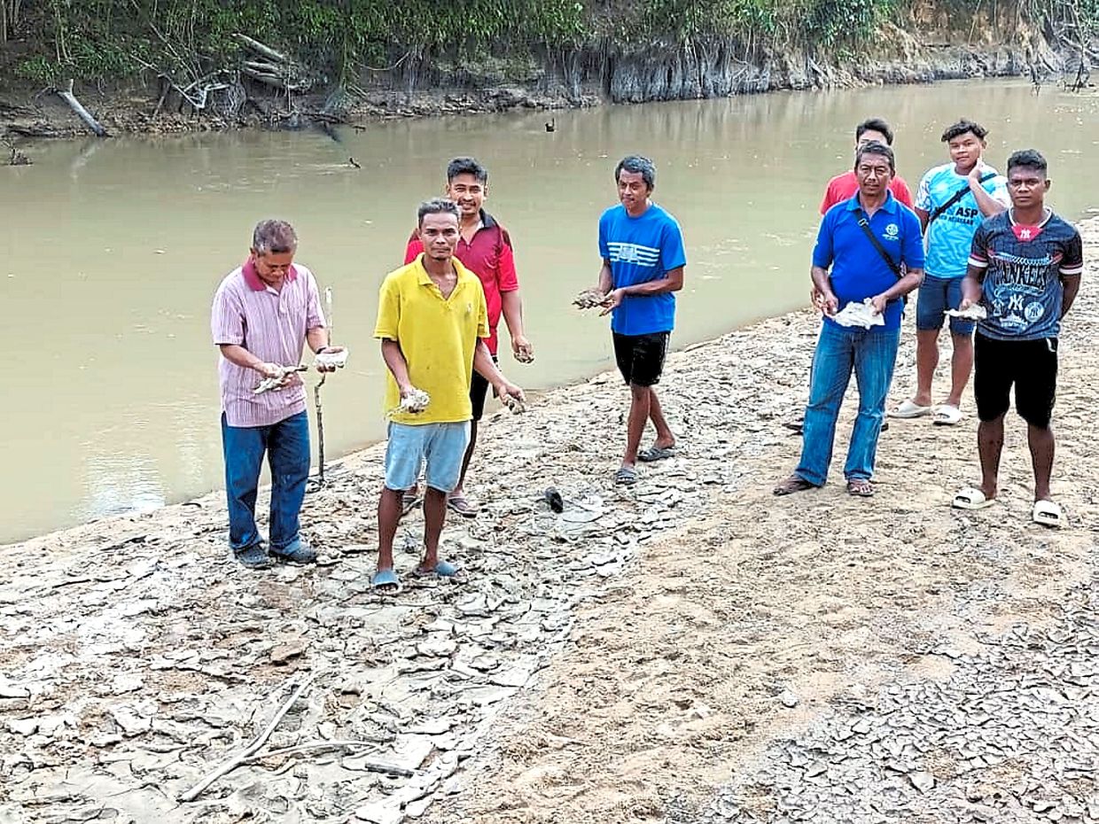 Kampung Orang Asli Sayong Pinang village chief Majid Jantan (left) and fellow villagers showing the effects of pollution in their village.