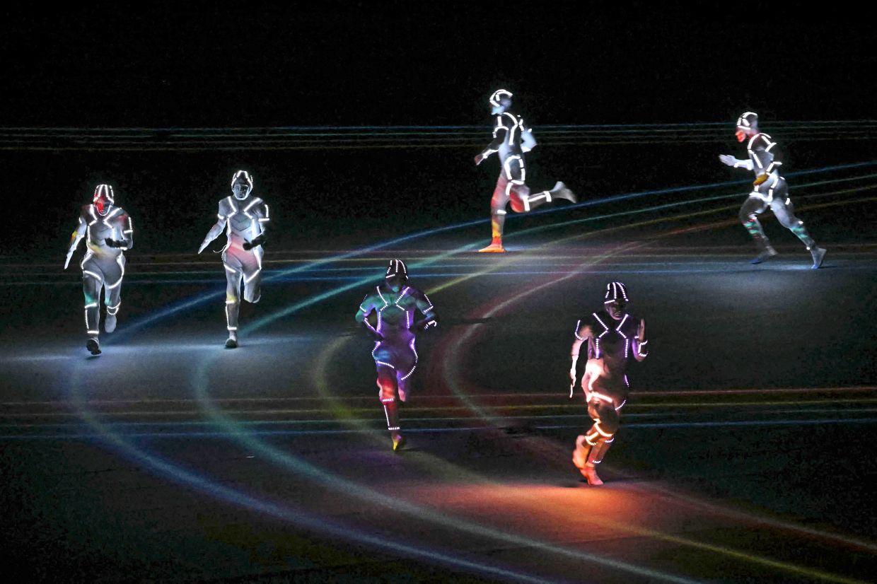 All lit up: Running and martial arts performers taking part in the opening ceremony. — AFP