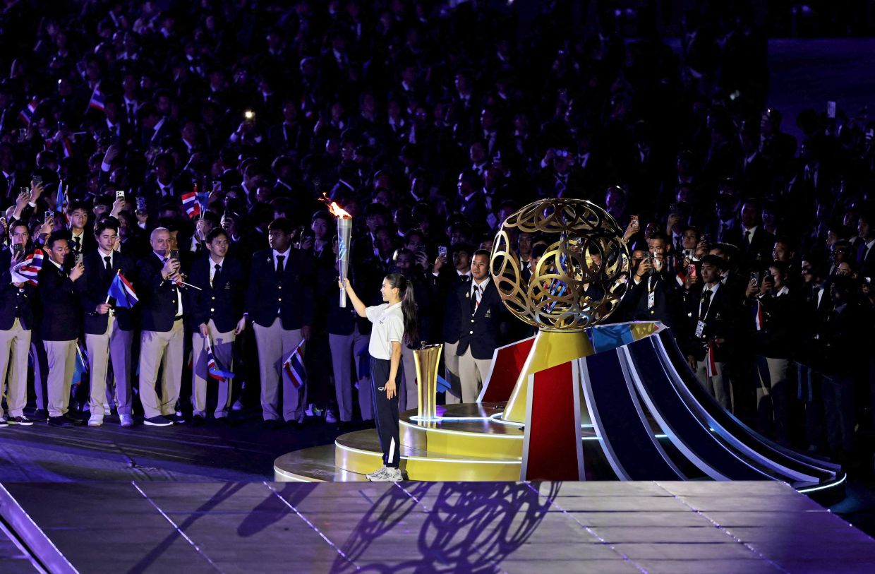Shining moment: Thai athlete and torchbearer Flying Officer Panipak Wongpattanakit seen ahead of placing the flame upon the small ceremonial cauldron during the opening ceremony. — Reuters