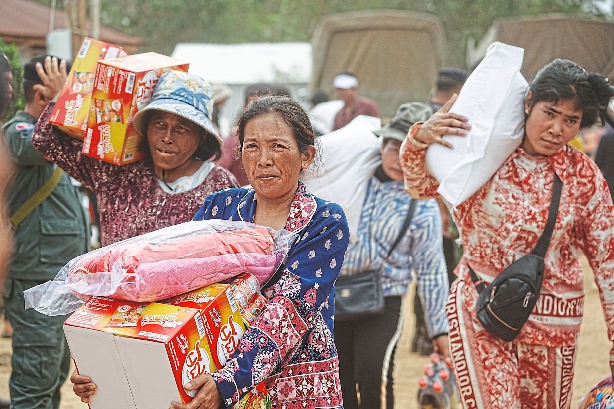 Evacuees receiving donation as they take refuge in Oddar Meanchey province after fleeing from home. — AP