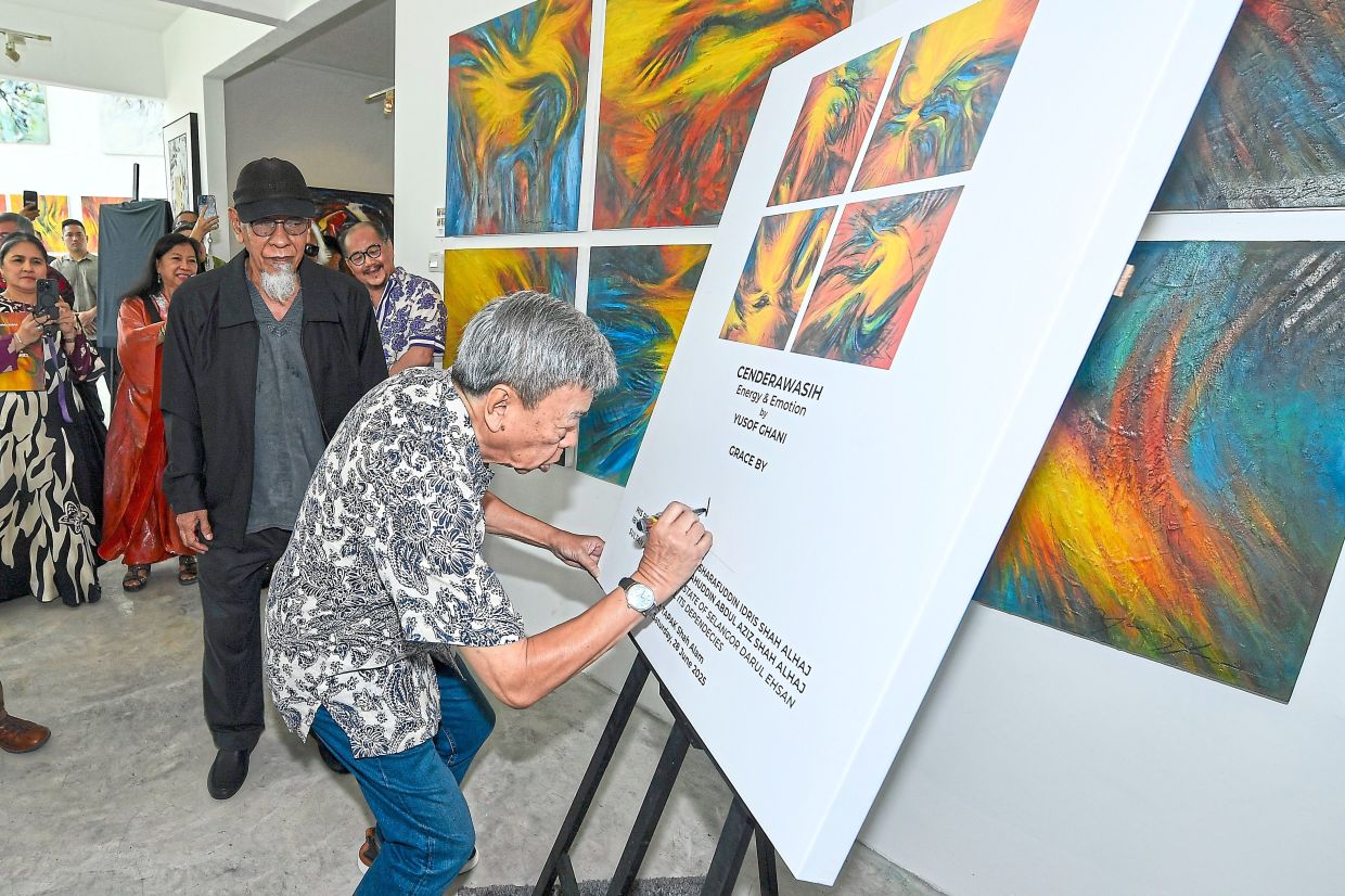 Sultan Sharafuddin signing a board to mark the launch of Yusof Ghani’s Cenderawasih: Energy & Emotion series at Tapak Gallery, Shah Alam, in June, as the artist looks on. — IZZRAFIQ ALIAS/The Star