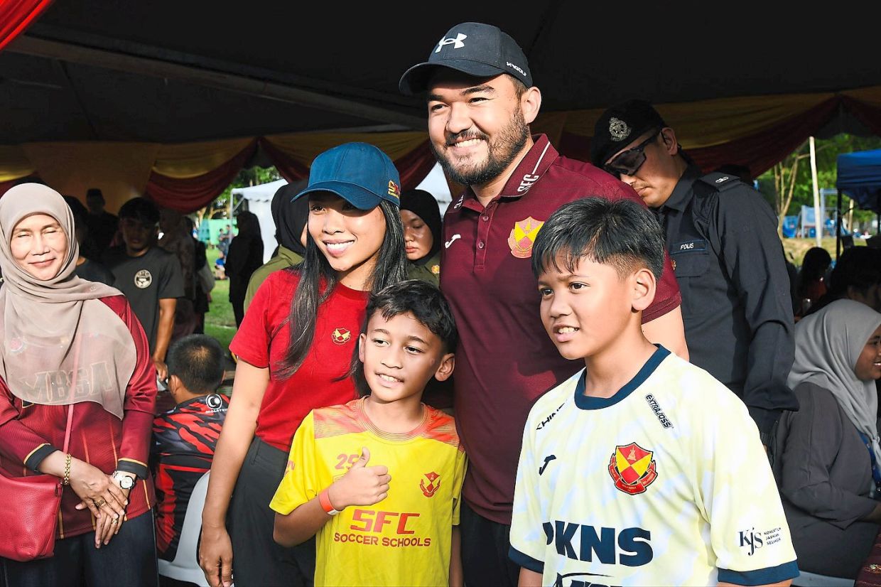 The royal couple posing for a photo with children during the People’s Sports Programme in Shah Alam in November. — Photos from Selangor Royal Office Facebook page