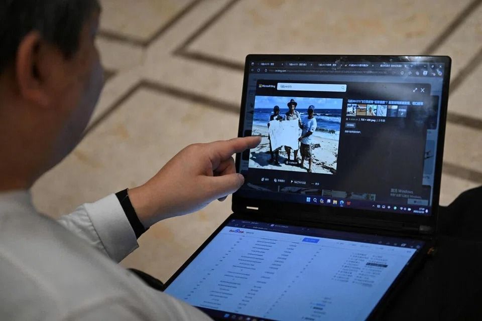 Jiang Hui is seen showing a picture of three people holding what appears to be a piece of debris at his home in Beijing on Dec 10. - Photo: AFP