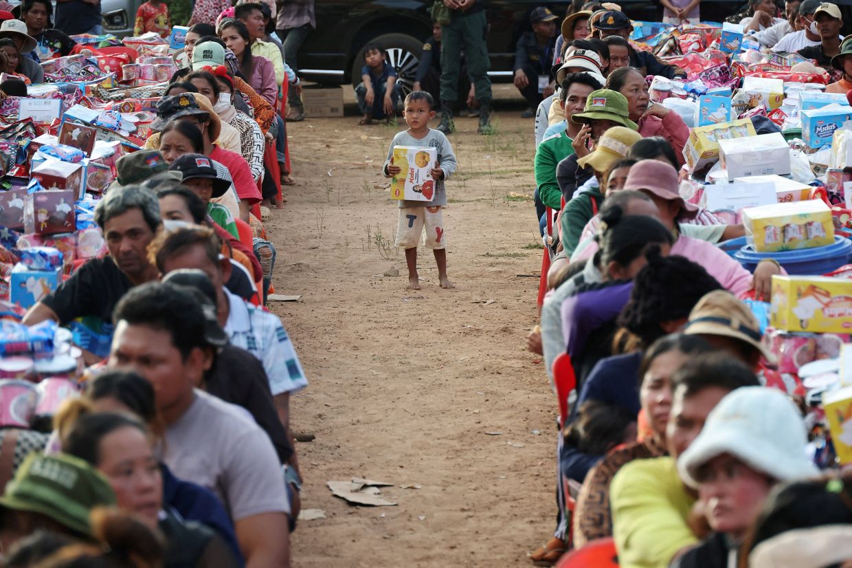 A boy holding a supply stands among people waiting to collect supplies at Batthkav refugee camp, amid clashes between Thailand and Cambodia along a disputed border area, in Chong Kal, Oddar Meanchey Province in Cambodia on Dec 12, 2025. - Reuters