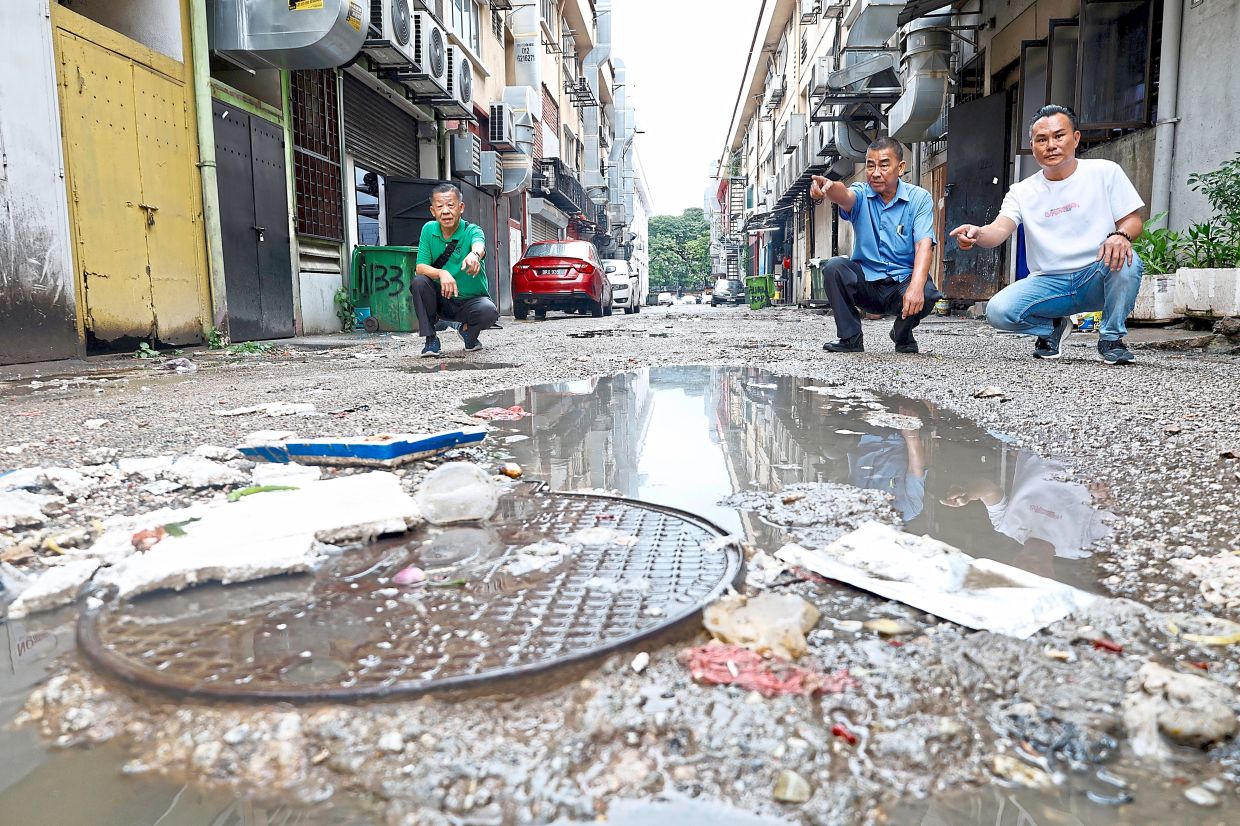 Kepong business owners say the EV charging stations should be relocated towards the end of the commercial block. — Photos: FAIHAN GHANI/The Star Yee (second from right) with Kok Kin and Fook Sang (left) showing the water-filled potholes behind the Jalan Rimbunan Raya 1 shop lots in Kepong.