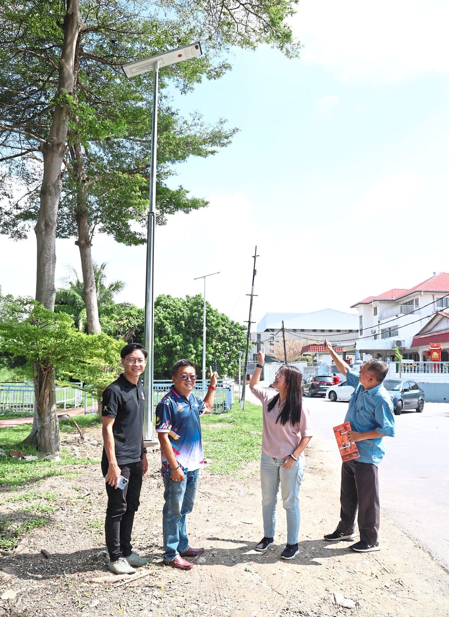 (From left) Tey, Housing and Local Government Ministry new village communications coordinator Tony Cheong, Siew Ki and Hong showing off the newly installed solar street lamps in Jalan Kuyuh, Kampung Baru Seri Kembangan.