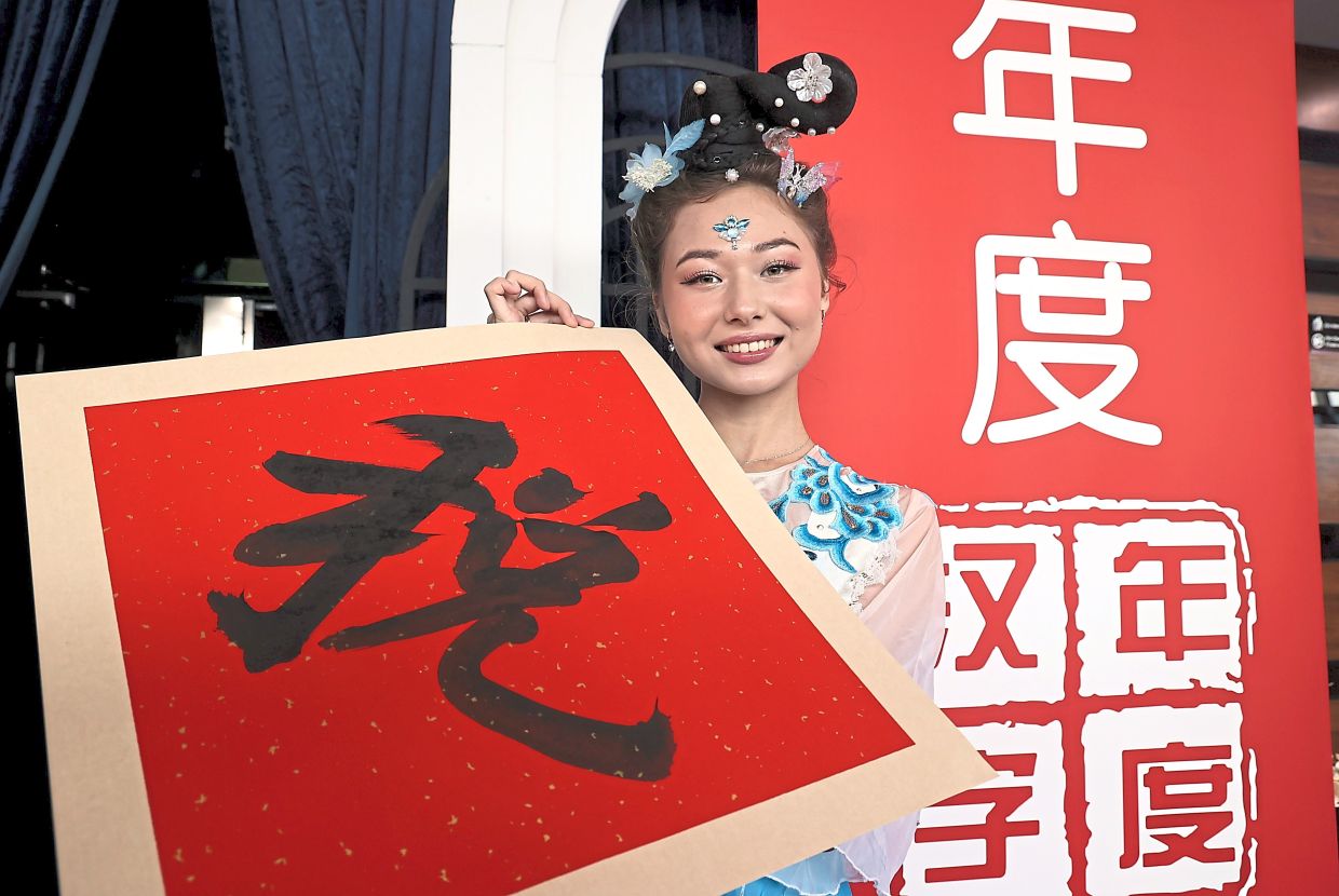 Tax talk: Kazakh dancer Alina Sultan posing with the Chinese character ‘shui’, meaning tax, which has been voted Malaysia’s Character of the Year at the unveiling ceremony. — ART CHEN/The Star