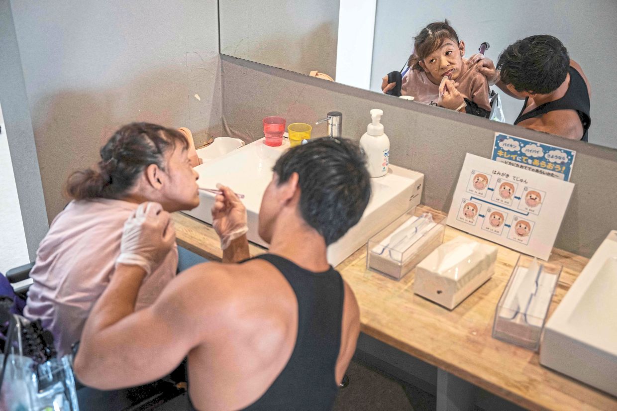 Fit and focused: (Left) Usui helping Yamaguchi brush her teeth at a care home for people with disabilities operated by Visionary in Ichinomiya, Aichi prefecture. — AFP