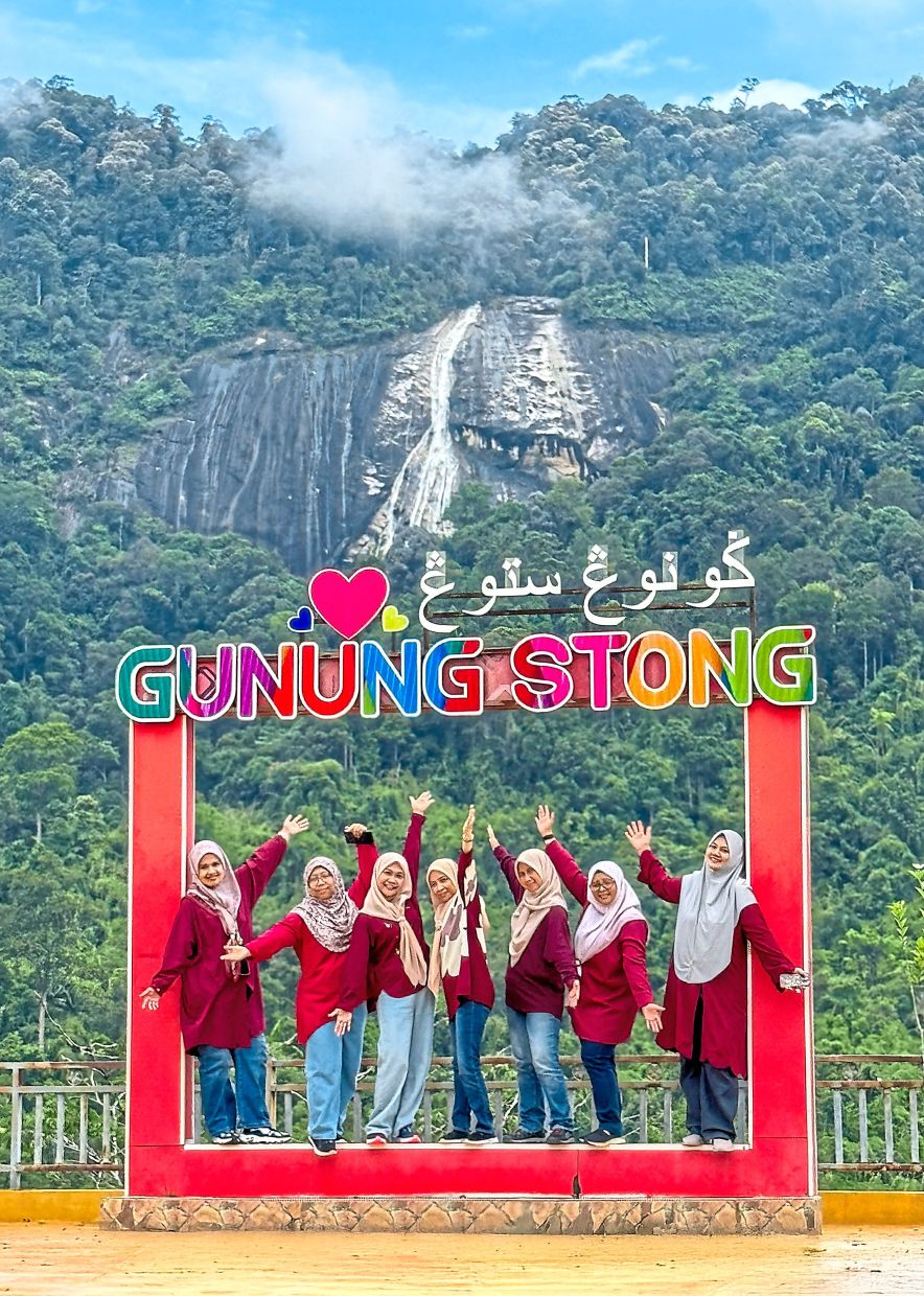 A stop at the Gunung Stong viewpoint, with the waterfall visible behind a group of visitors.