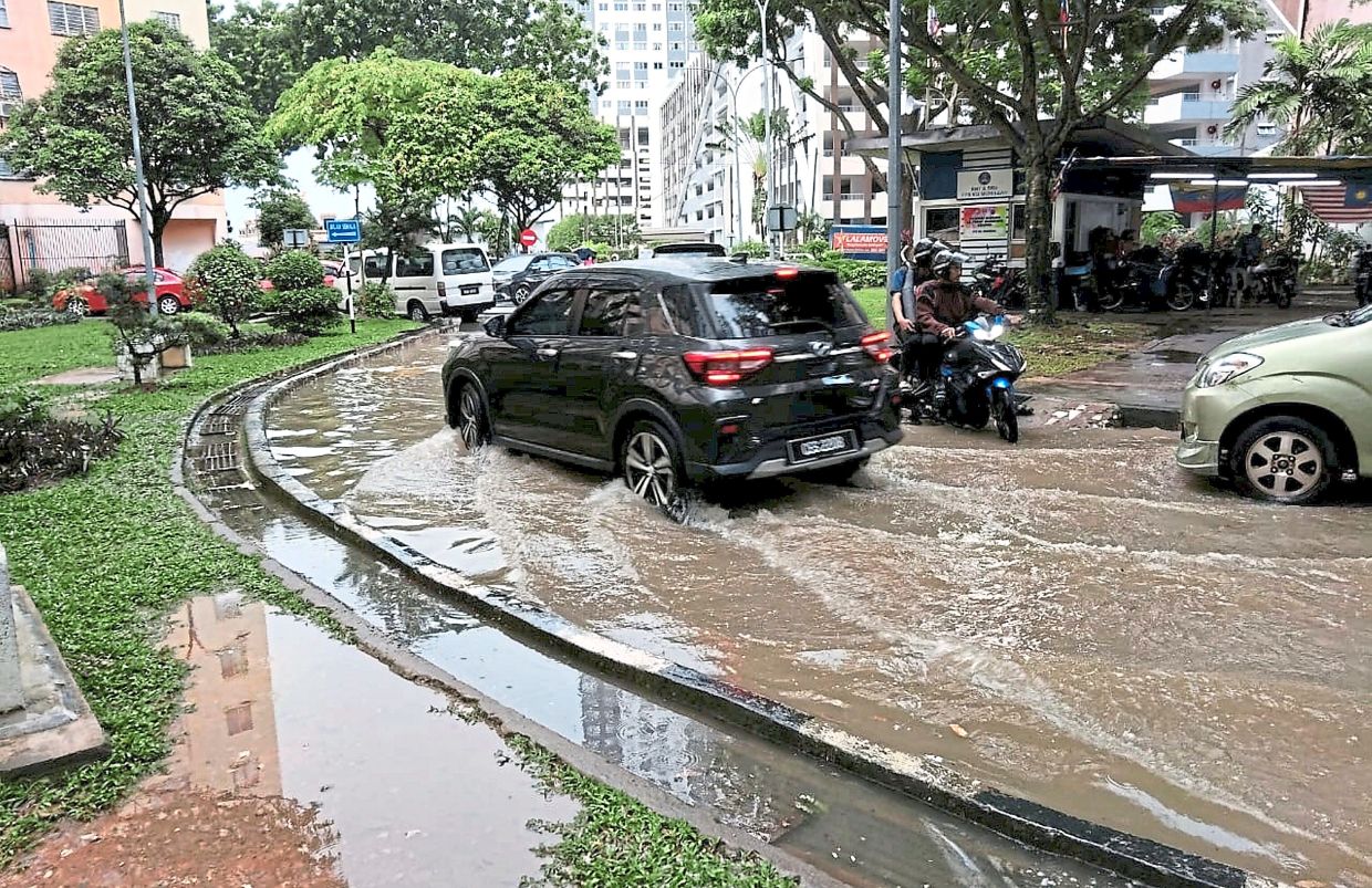 Motorists making their way through floodwaters along an internal road at PPR Kampung Muhibbah following heavy rain earlier this month.