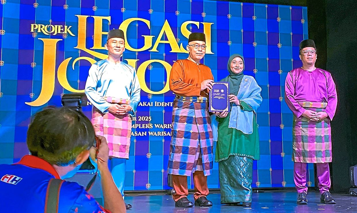 Johor Baru district officer Mohd Masni Wakiman (second from left) presenting the offer letter for the weaving course to Noor Amira. With them are Rozaini (left) and Johor Heritage Foundation director Nor Syazlan Abd Razak (right). 