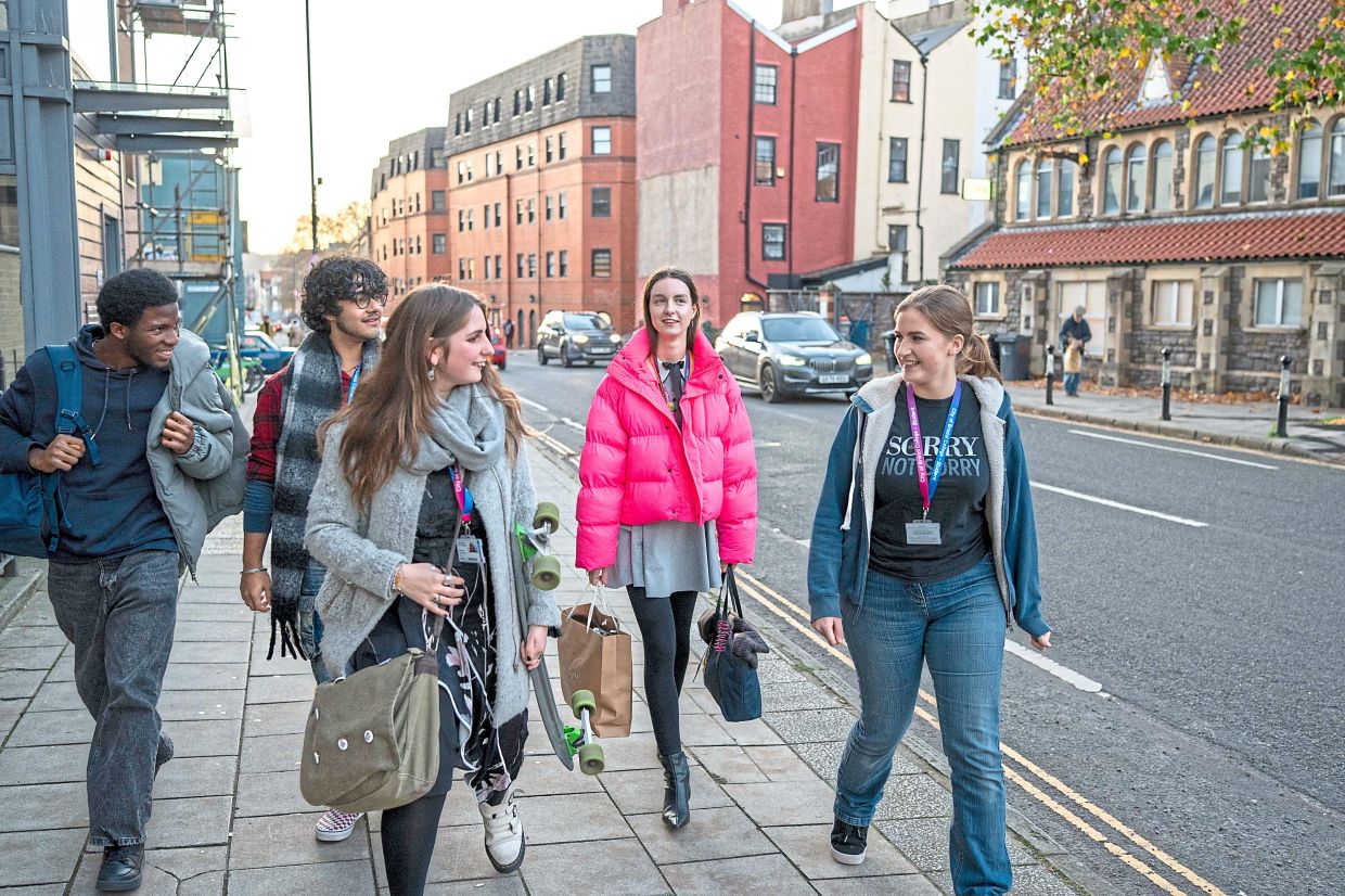 Williams (right) walking with other young people on a street in Bristol. — Andrew Testa/The New York Times